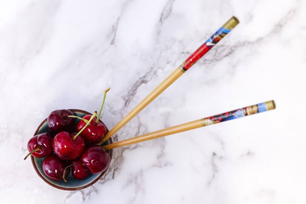 bowl of cherries on marble background with chopsticks