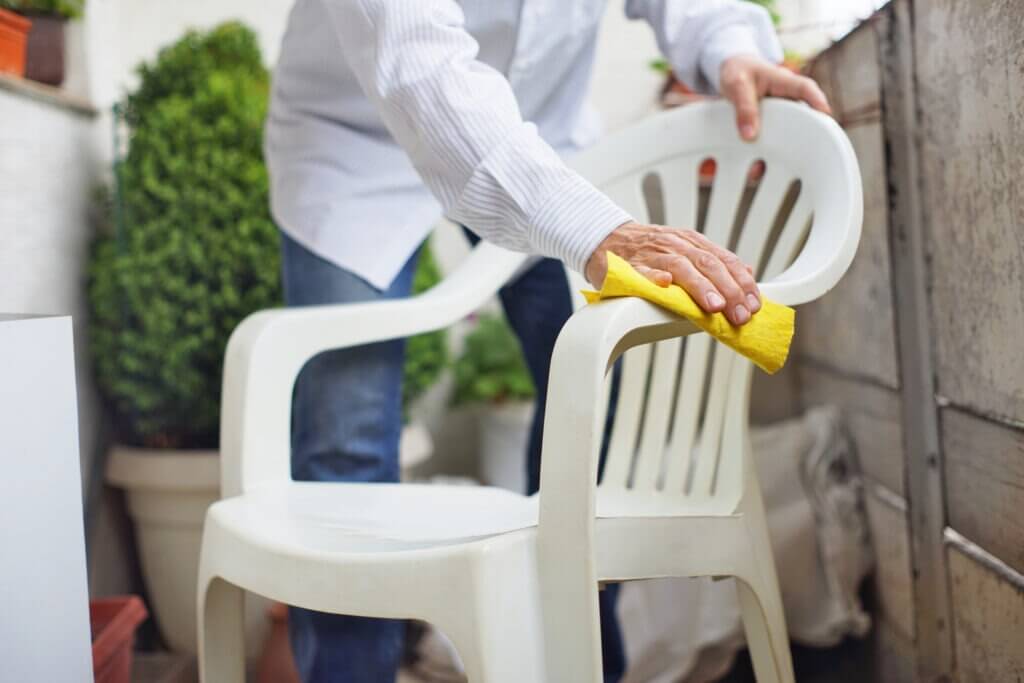 A man wipes a plastic garden chair