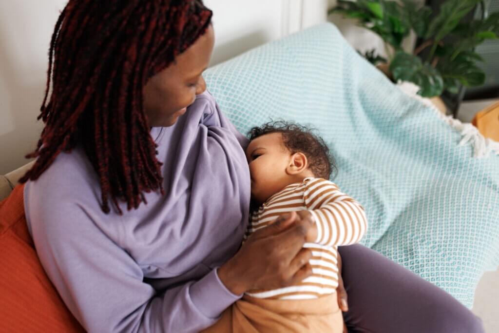 Woman breastfeeding baby boy at home