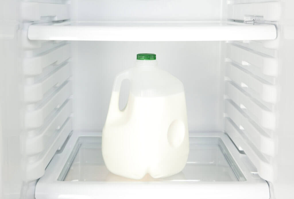 "A gallon jug of milk inside of a refrigerator, close-up.Please also see:"