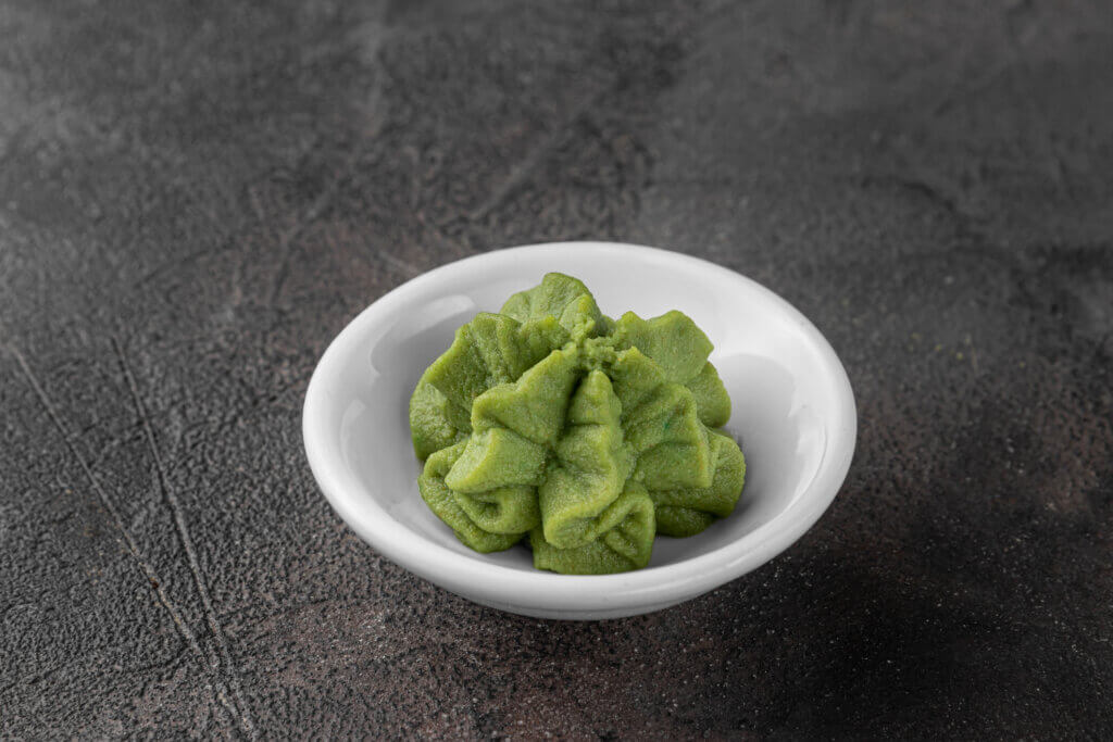 white ceramic bowl with a wasabi sauce for sushi. dark gray textured background, side view