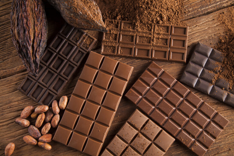 Chocolate bars and cocoa pod on brown background