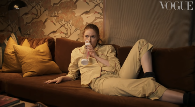 Karen Gillan drinking water on her couch during a celebrity home tour