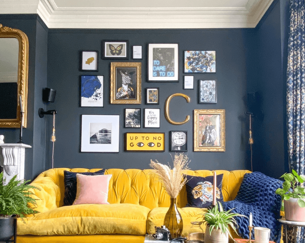 Gallery wall with yellow couch and navy blue wall