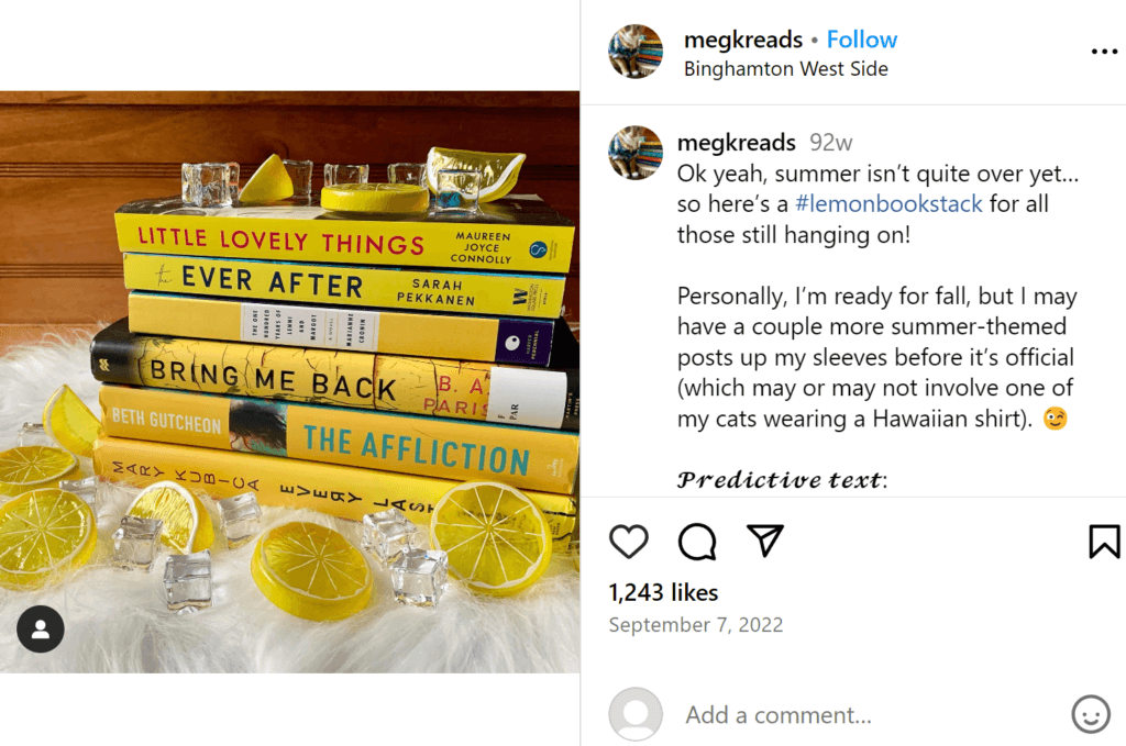 Yellow stack of books decorated with plastic lemon slices and clear plastic ice cubes for a lemony theme, sat on a sheepskin throw.