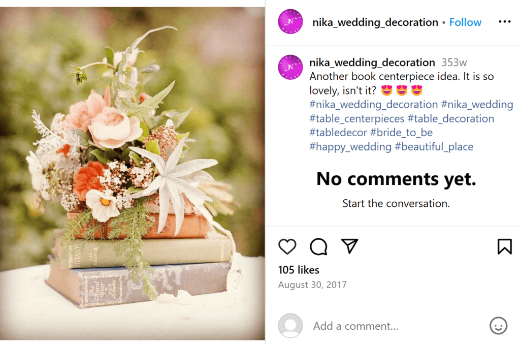 Pink floral wedding centerpiece with a stack of pink and blush books underneath the flowers.