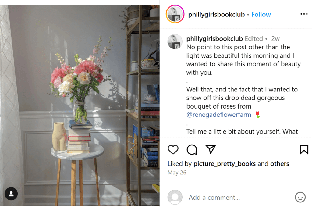 Small, narrow stack of pink and blue books stacked and holding a vase of pink flowers on an end table next to an anatomical sculpture.