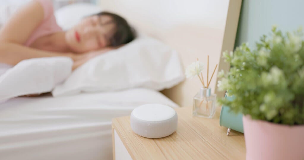 Closeup side view asian woman lying on bed using white noise machine helping sleeping quality