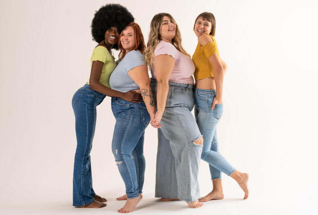 Multiracial group of women holding hands and looking at camera.