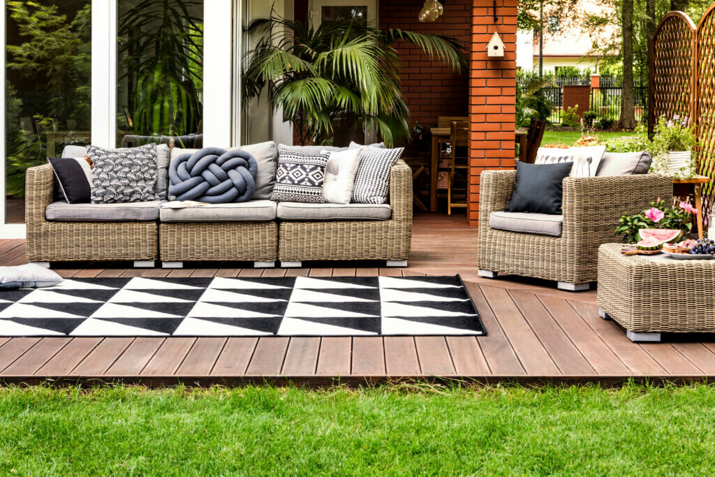 Rattan sofa and armchair with pillows on a wooden terrace of a modern house