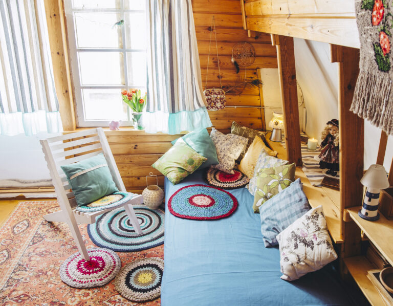 Maximalist maximalist home concept. Holiday home cabin bedroom with natural wooden board walls and ceiling and lot of different color details.