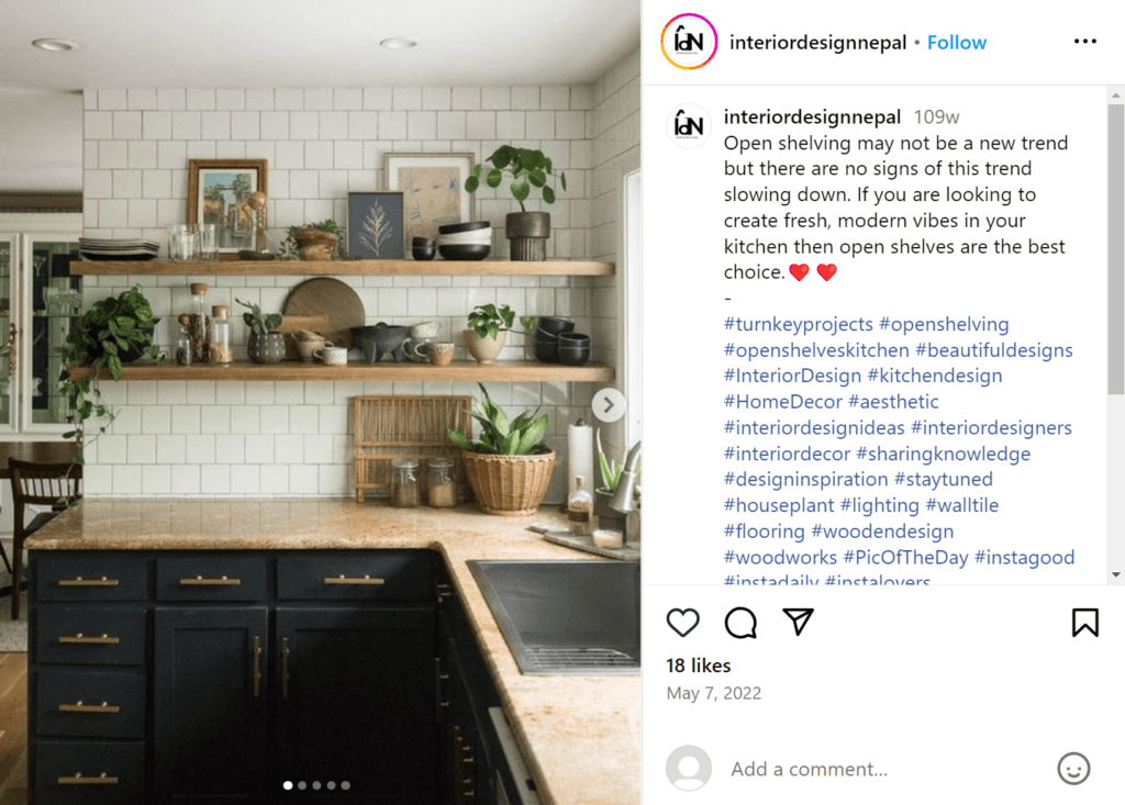 Wooden open shelves on a white tile backsplash above dark grey kitchen cabinets, with the shelves featuring decorative kitchen items, plants, and framed drawings.