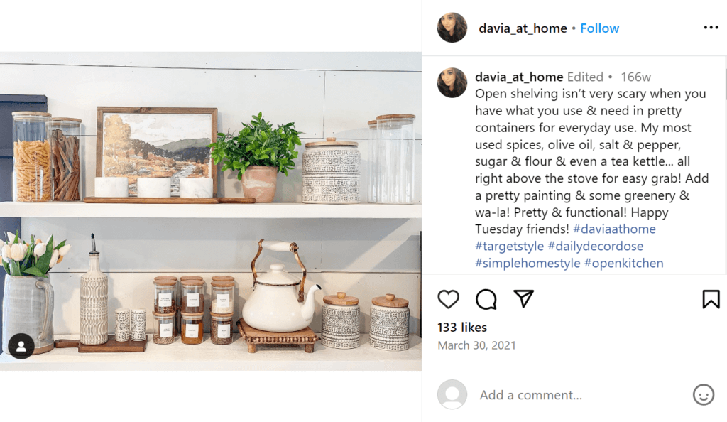 White open shelving with various canisters containing pasta and spices, as well as a white old-fashioned teapot.