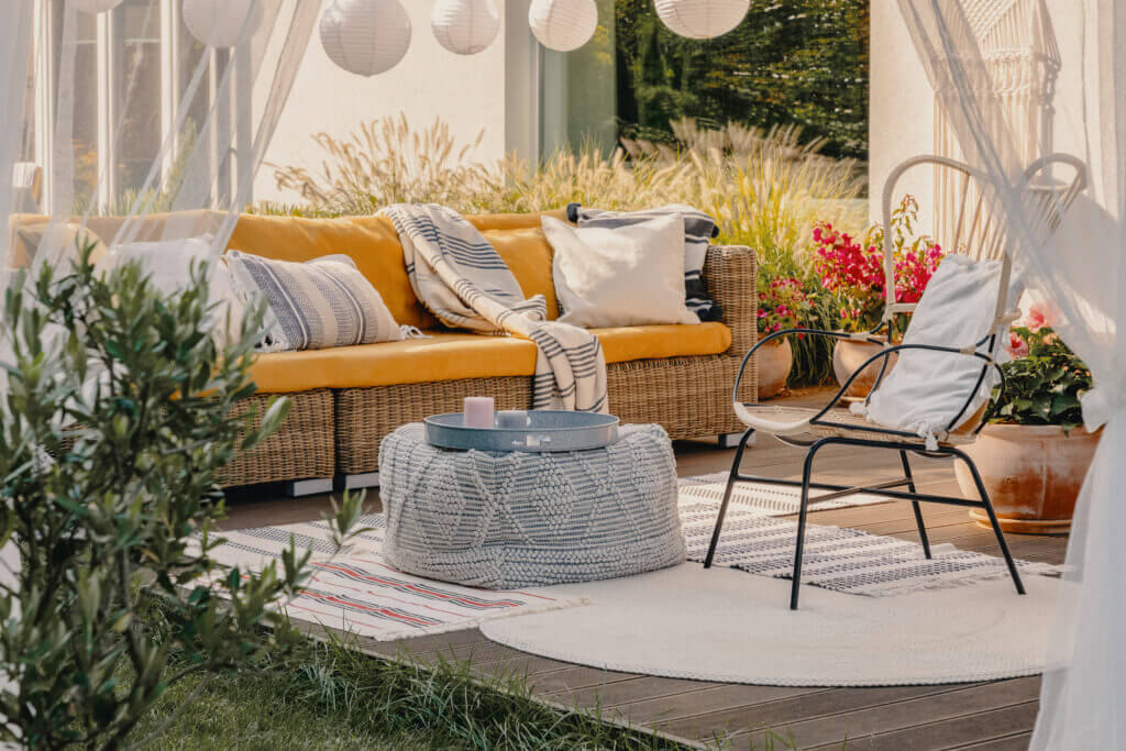 Real photo of an armchair, pouf as a table and wicker couch on a terrace