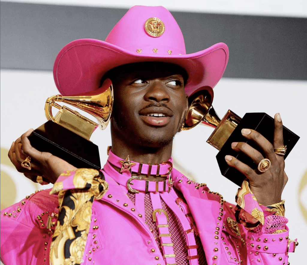 lil nas x in pink outfit posing with grammys