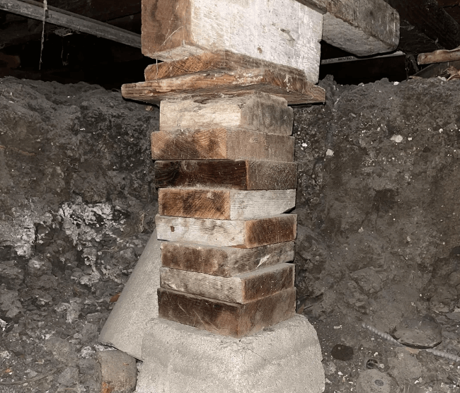 DIY support pillar in a basement with numerous shims holding it up