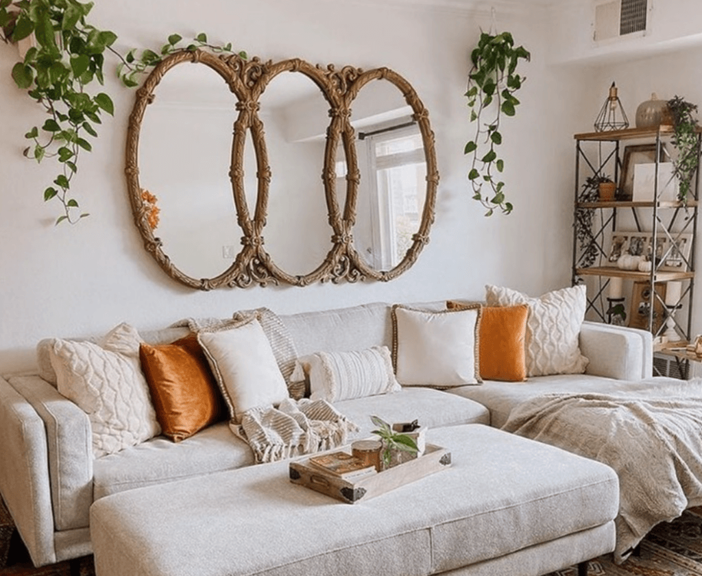 Clean bohemian living room with a decorative triple-mirror behind the couch.