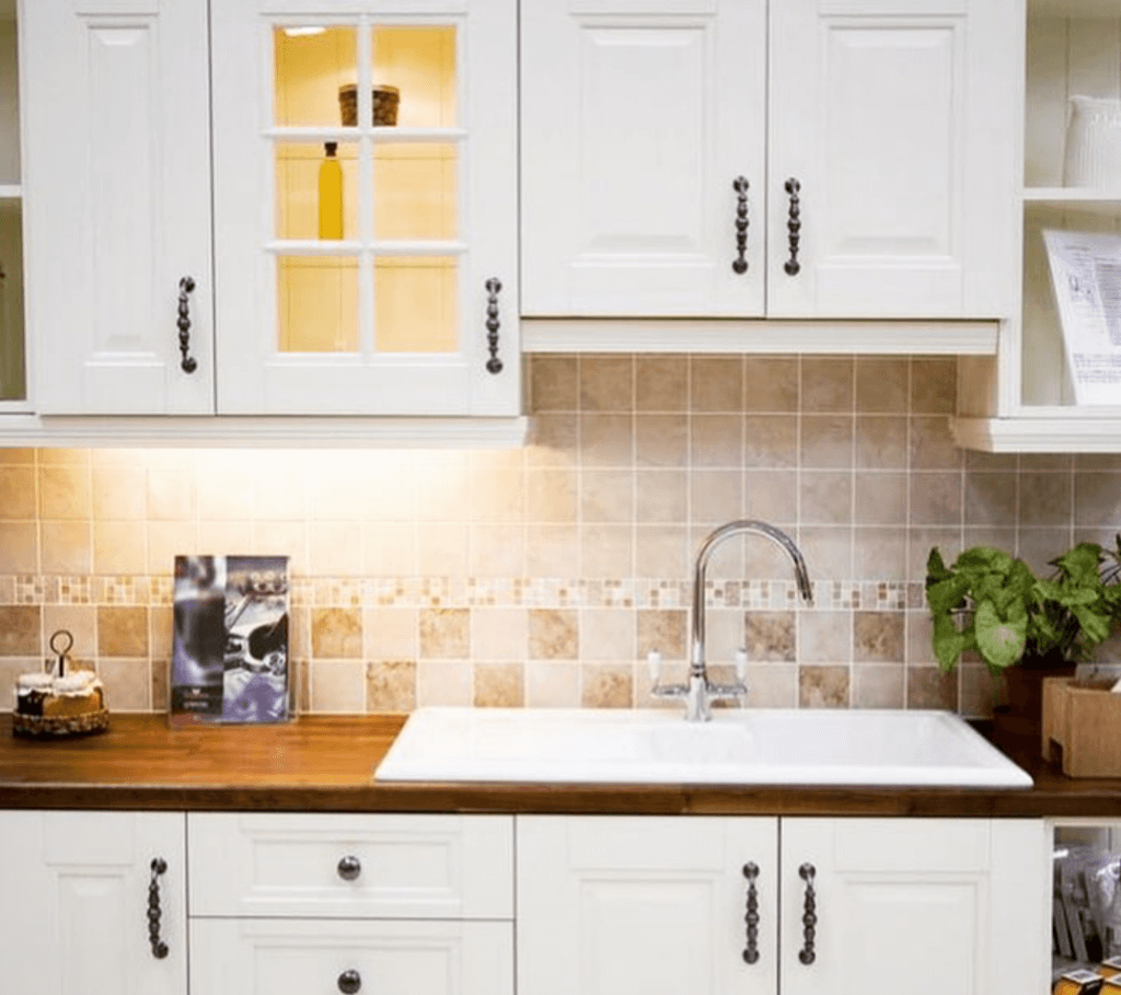 White cozy kitchen with one cabinet panel replaced with a glass window-style panel