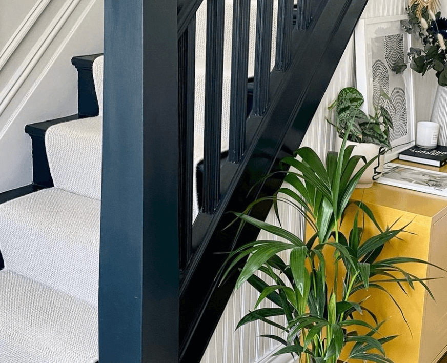 Narrow staircase with newly painted navy blue banister and white runner