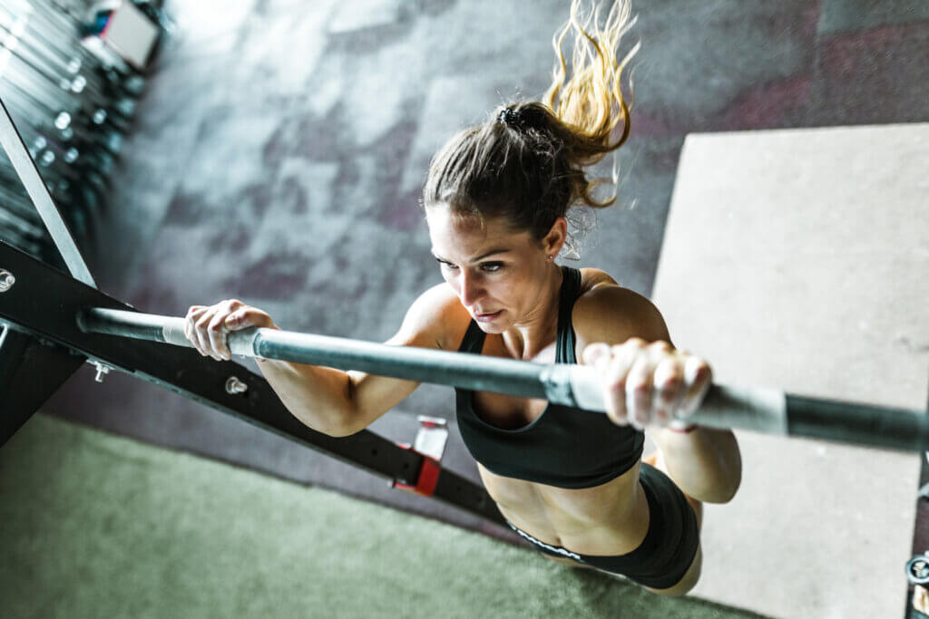 Above view of athletic woman exercising chin-ups in a gym.