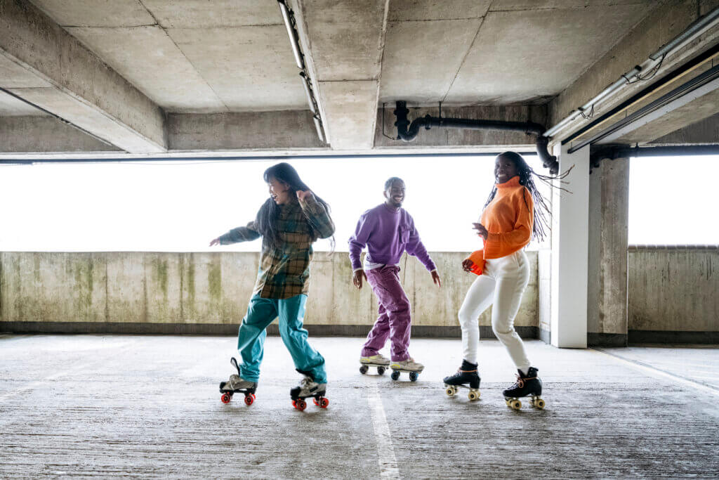 Full length view of Black and Asian freestylers smiling and laughing as they warm up together in concrete garage.