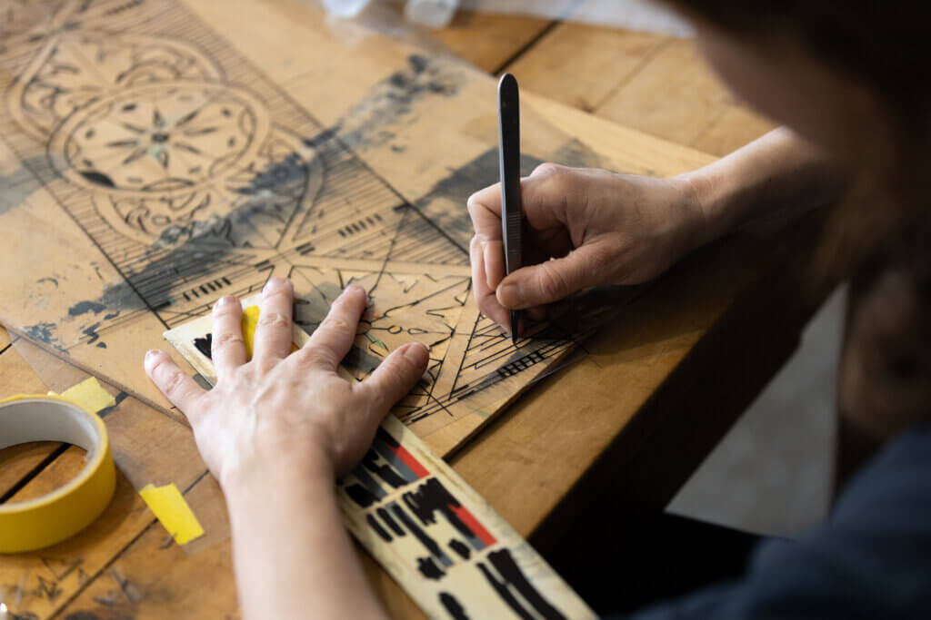 Adult Caucasian Female Expertise Cutting a Wall Stencil Design in her Studio Workshop