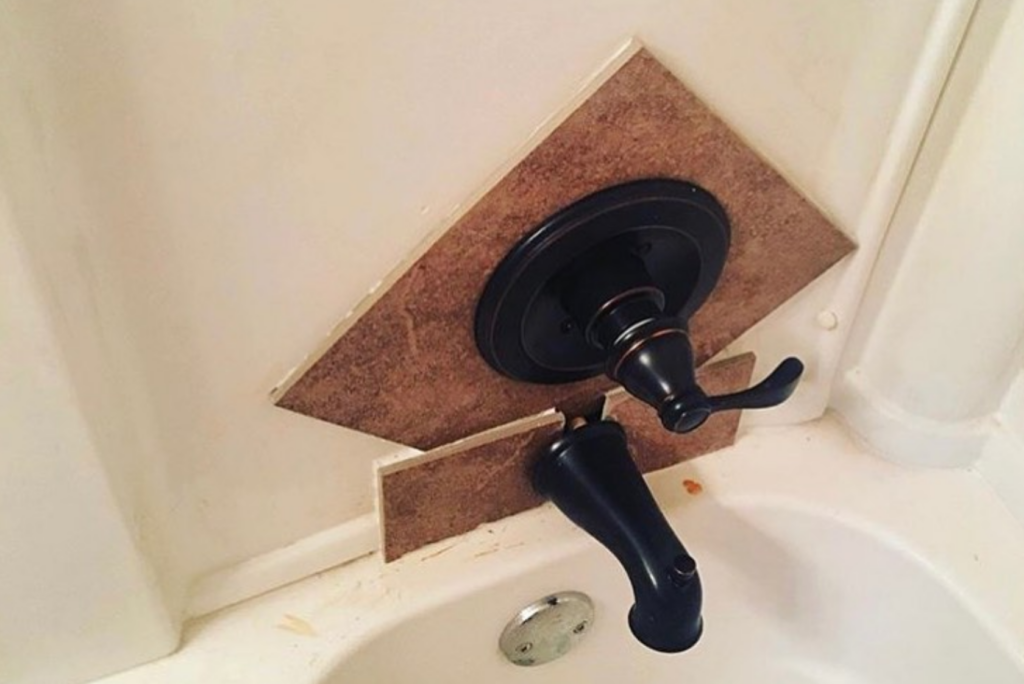 A bathtub faucet installed with mismatched tiles awkwardly cut and placed around it. The tiles are not aligned and appear to have been hastily added to accommodate the faucet, resulting in a visually unappealing and unprofessional look.