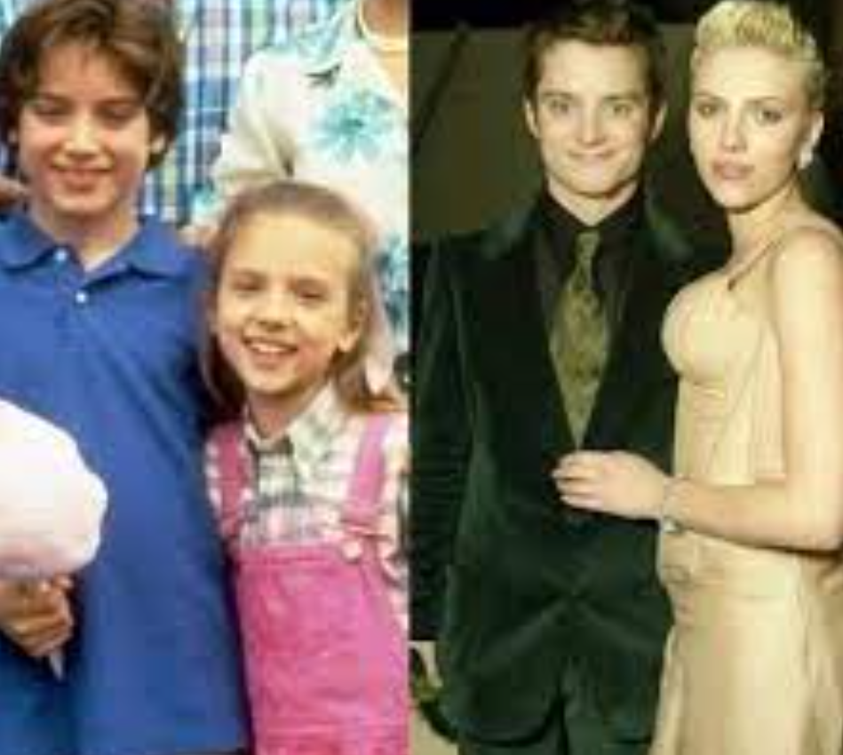 A side-by-side comparison shows Scarlett Johansson and Elijah Wood in two different time periods. On the left, they are young children; Scarlett is wearing pink overalls, and Elijah is in a blue shirt, both smiling brightly. On the right, as adults, Scarlett wears an elegant dress and Elijah a suit, posing together at a formal event.
