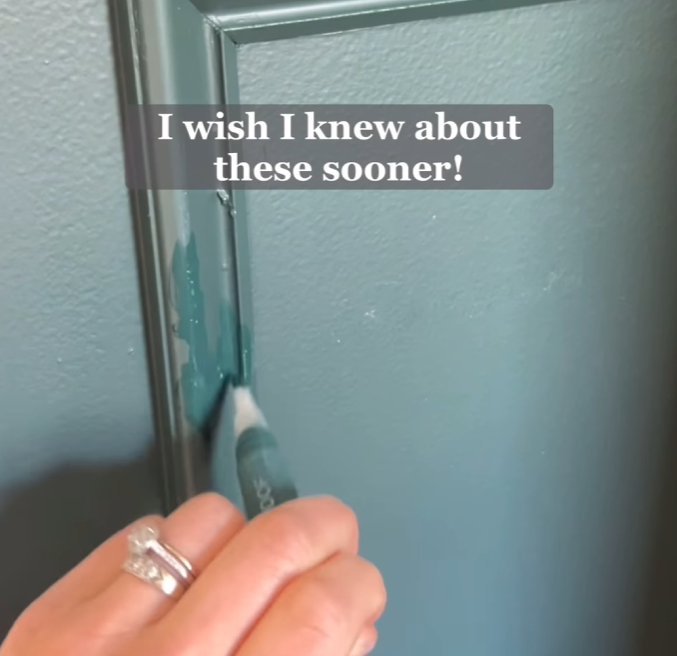 A hand holding a paint touch-up pen is seen applying teal paint to a door frame. The text overlay reads, "I wish I knew about these sooner!" highlighting the convenience of the touch-up pen for quick fixes.