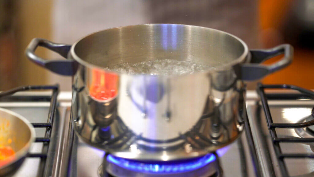 Professional chef cooking in domestic kitchen: Boiling water for tomato spaghetti preparation