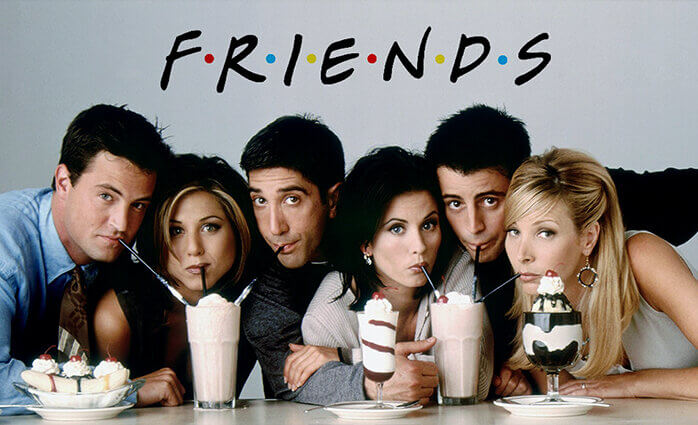 The cast of the sitcom "Friends" posing next to each other, drinking millkshakes