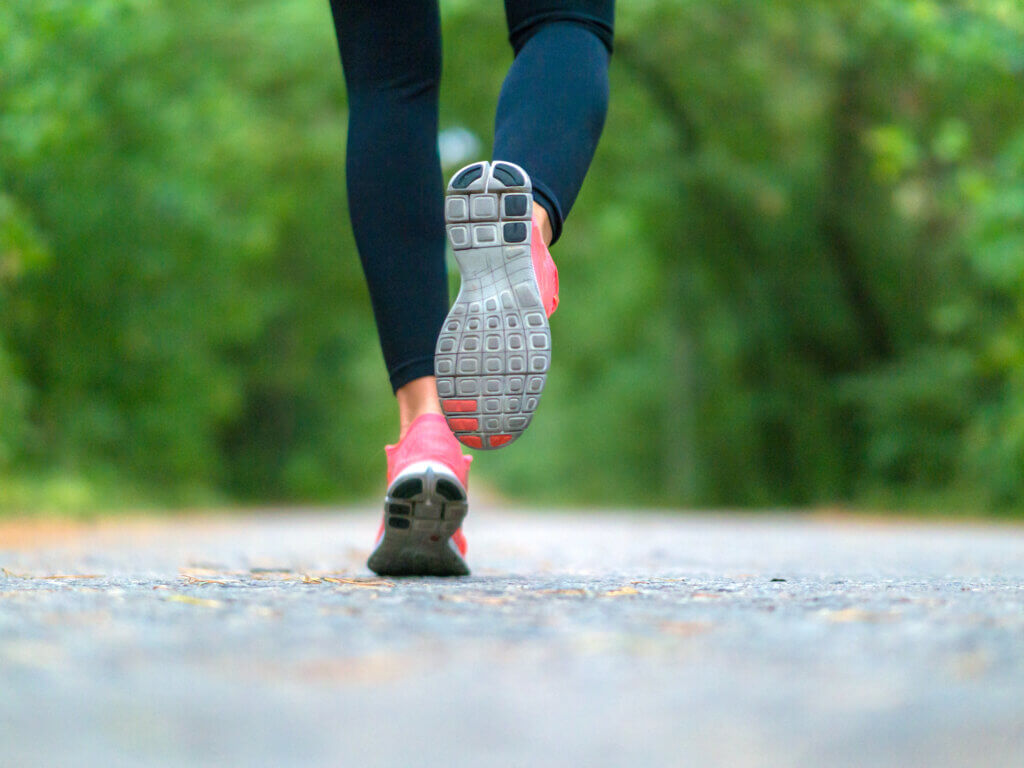 Running woman in the forest. Close-up of sneakers. 