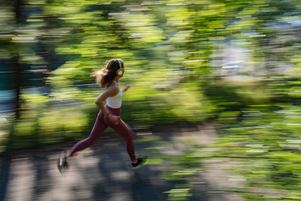 female athlete running through forest, blurred background