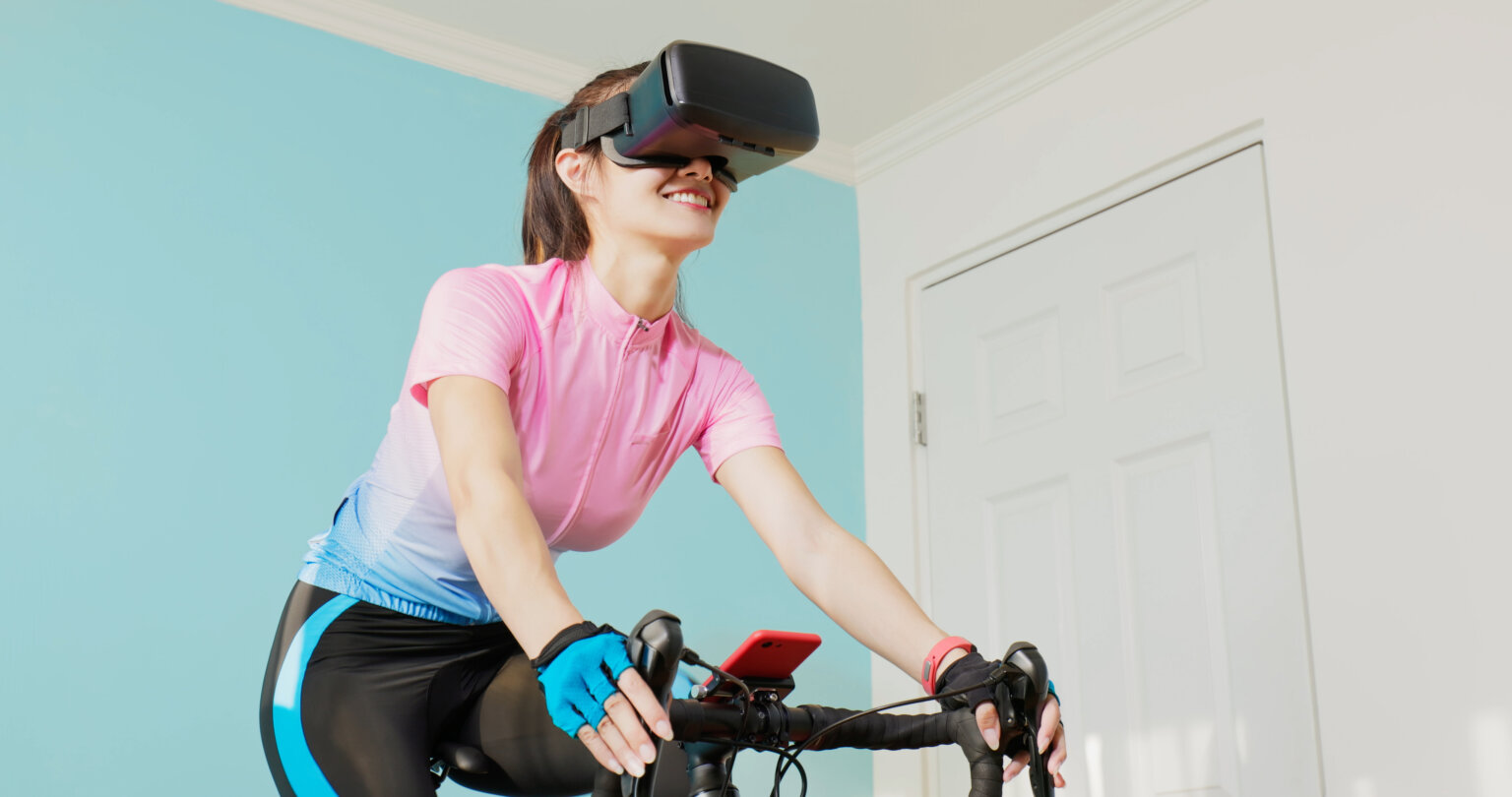 woman cycling with VR glasses in her room