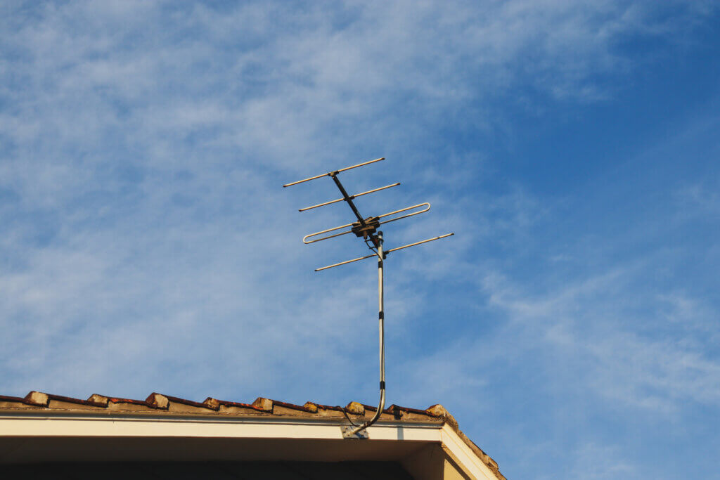 television antenna on house roof against blue sky