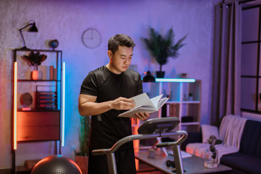 man reading book while on treadmill