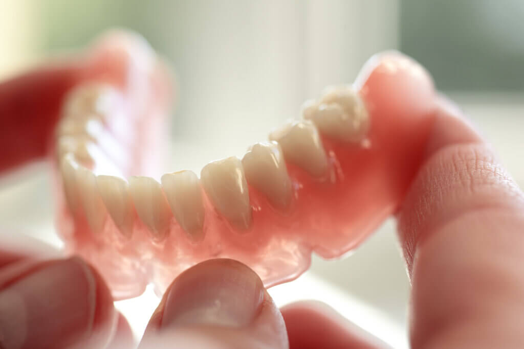 Dental technician holding a denture.