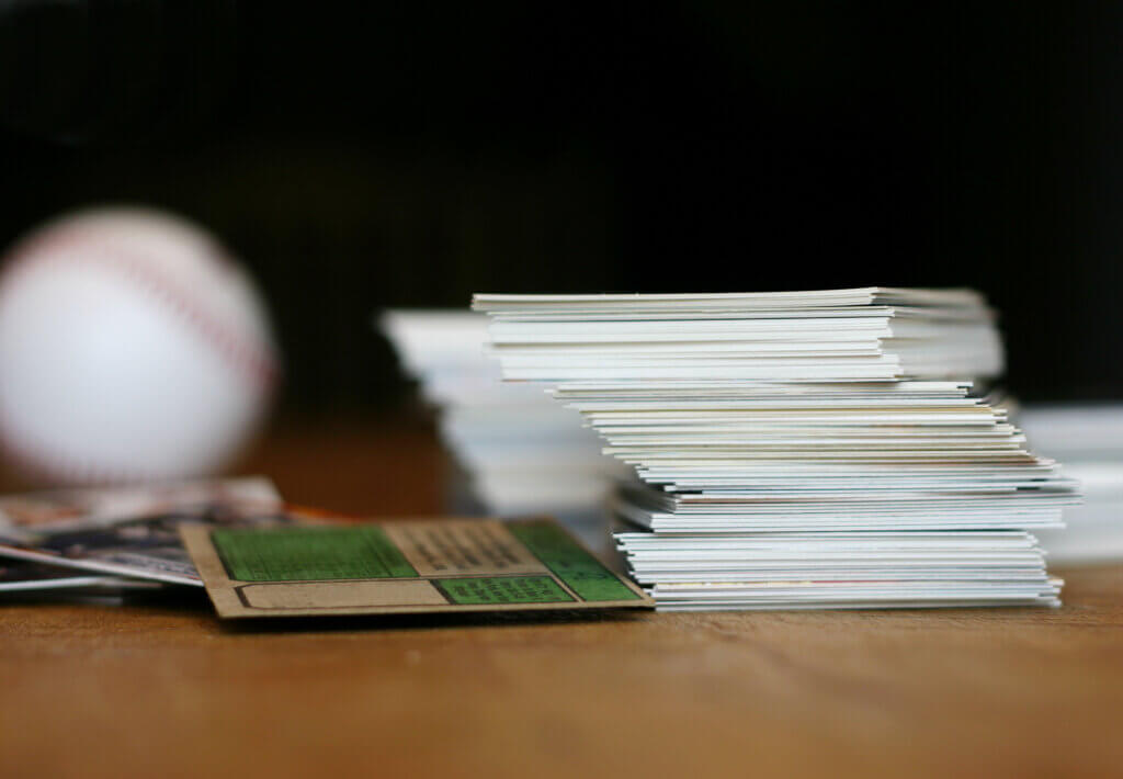 "Collection of baseball cards and baseball on old wooden table. Shallow dof, focus on stack of cards baseball in background is out of focus."