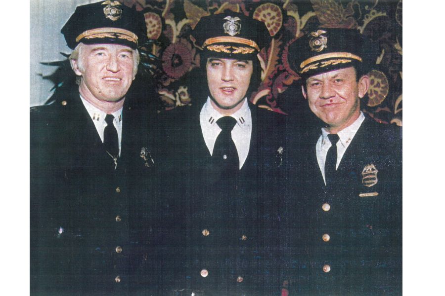 Elvis wearing a police uniform standing next to two police officers