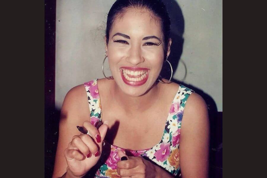 Teenage Selena Quintanilla smiling while holding a pen