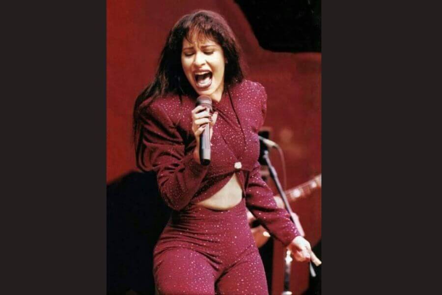 Selena perfoming on stage wearing a burgundy suit