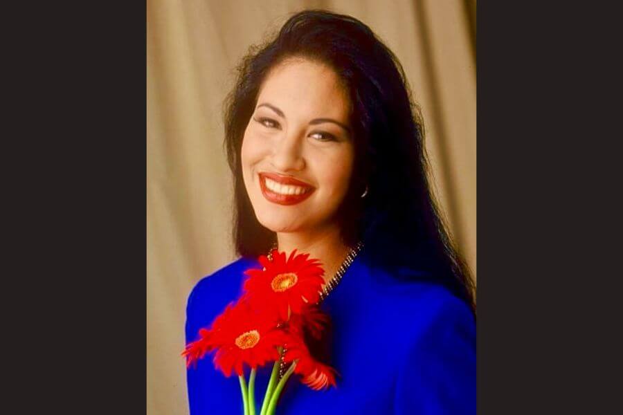 Portrait of Selena Wearing a blue suit holding a red flower