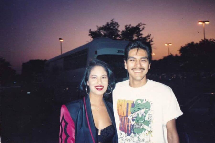 Selena hugging a young man. You can see a bus in the background. 