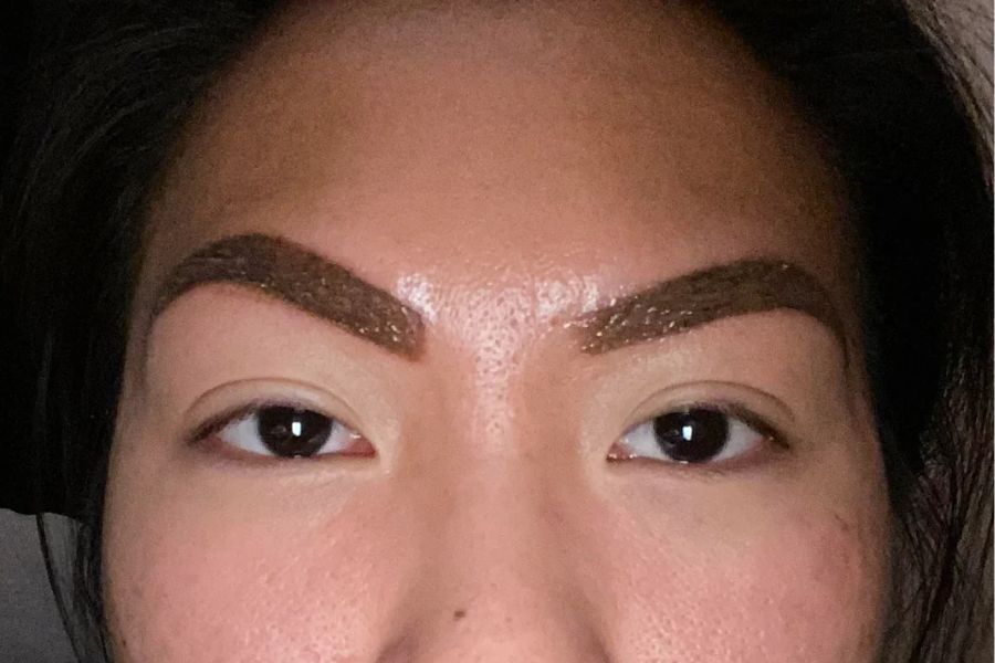 A close up to an uneven microblading job on an asian woman's face.