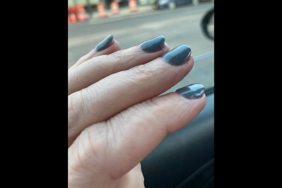 A hand showcasing badly painted nails with blue nail polish.