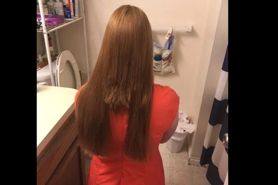 A picture taken from the back of a girl with long bronw hair and a chopped in the middle