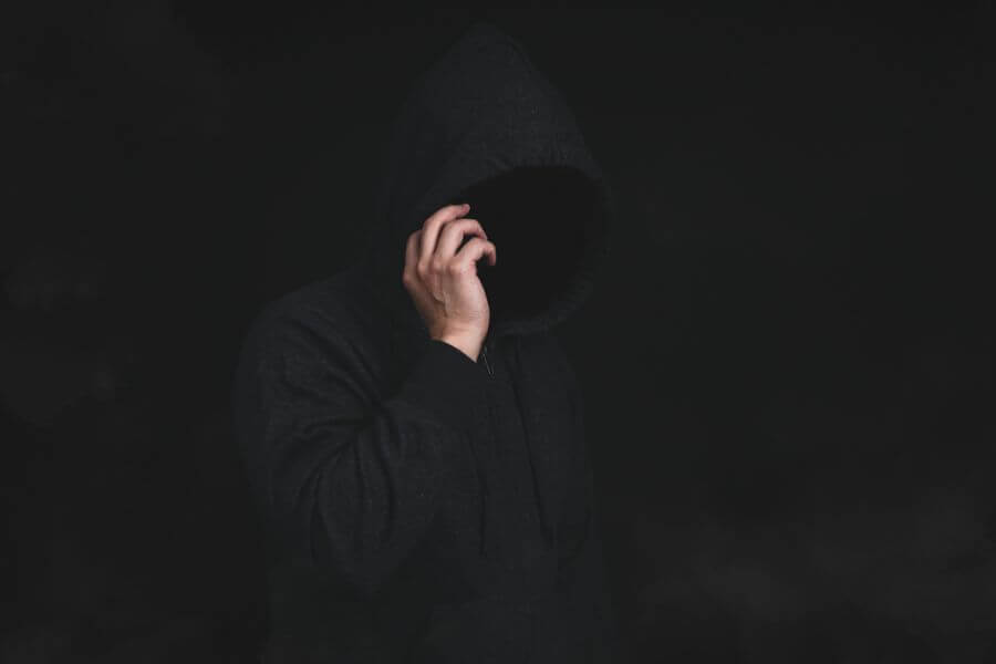 
Man in hooded jacket using cell phone in dark background