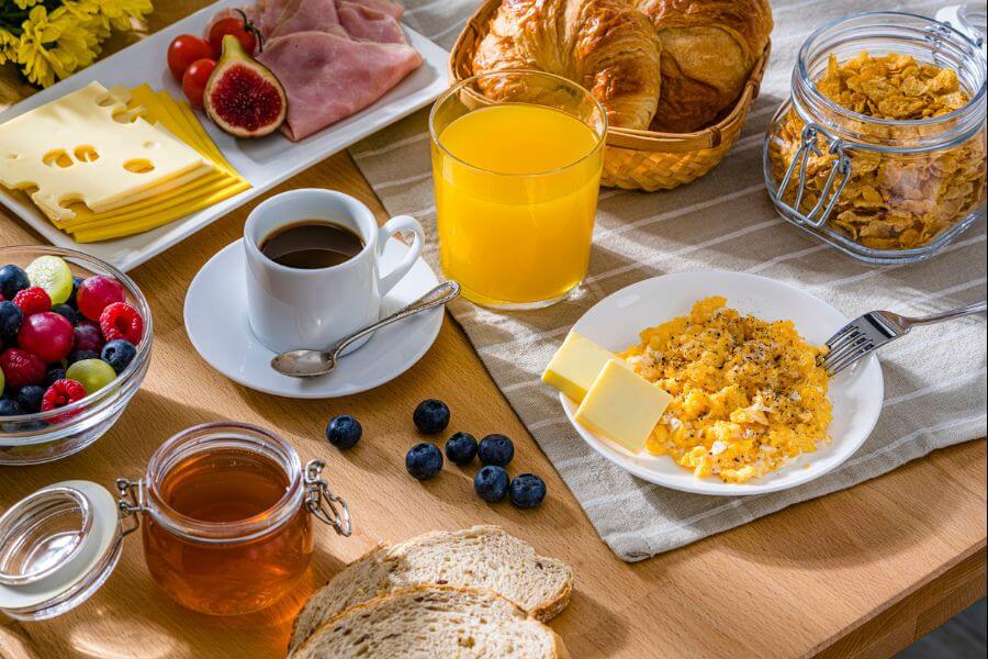 Healthy breakfast of scrambled eggs, cheese, ham, coffee, croissants and fruit juice