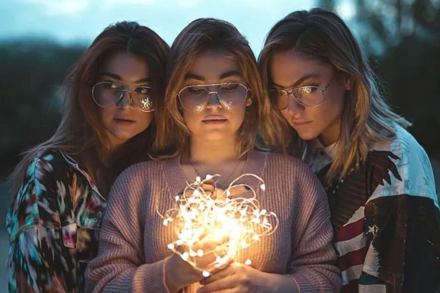 three young woman holding a light bolb