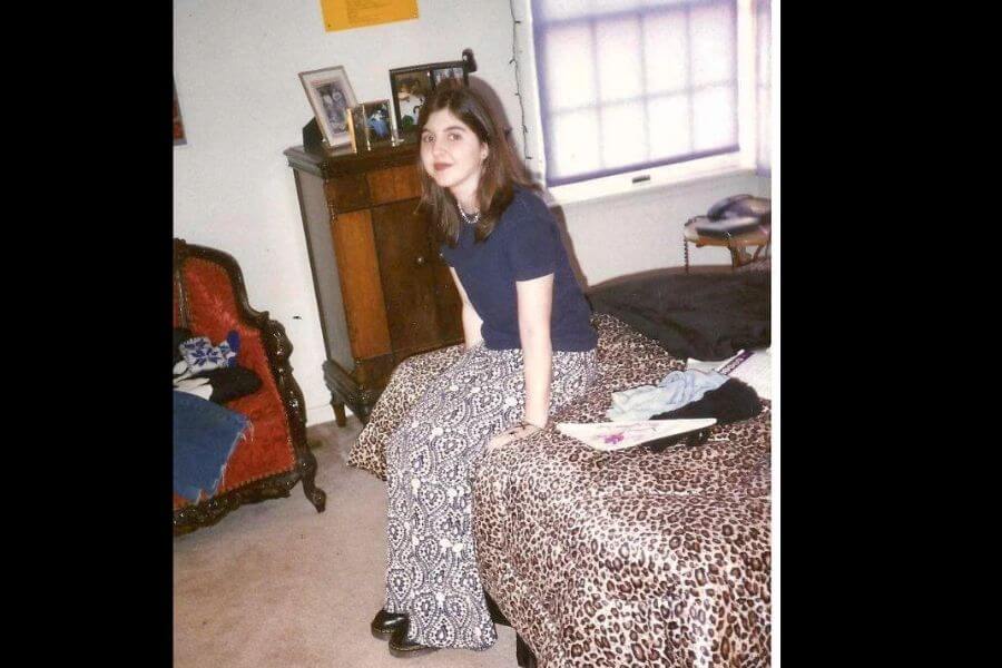 young woman sitting on bed wearing leopar print trousers